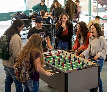 students hanging out in the SJC suns lounge playing fooseball.